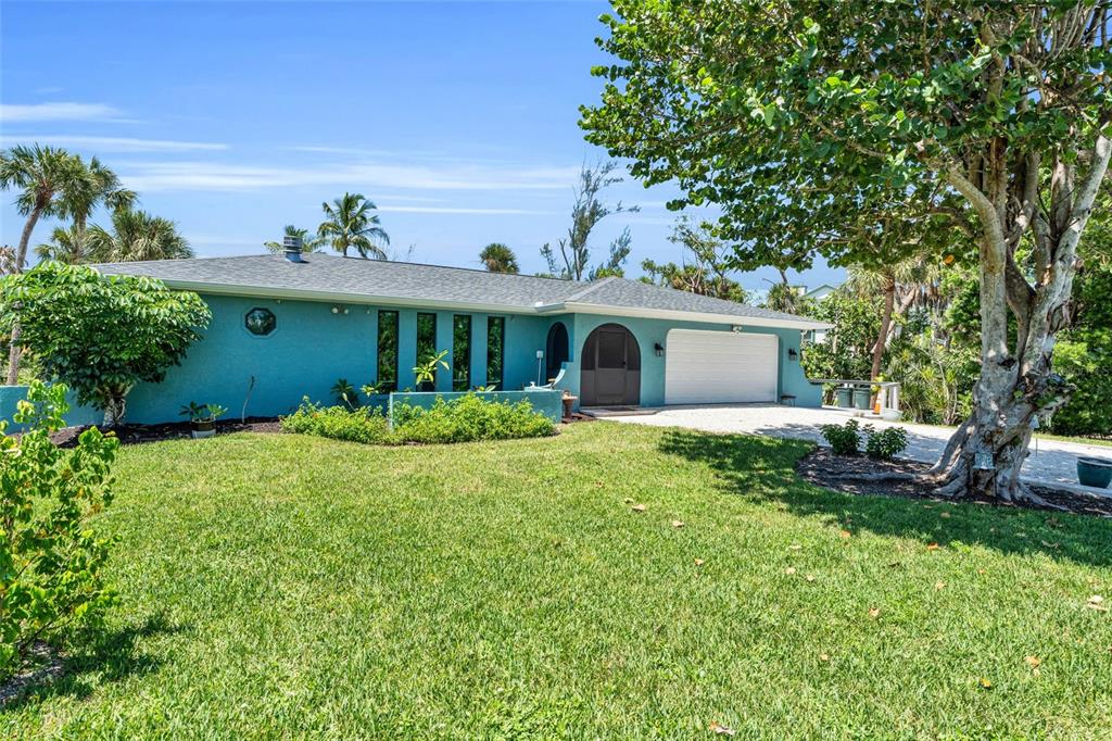 A teal, single-story house with a white garage door and a large tree in front — 4636 BUCK KEY ROAD, SANIBEL, FL