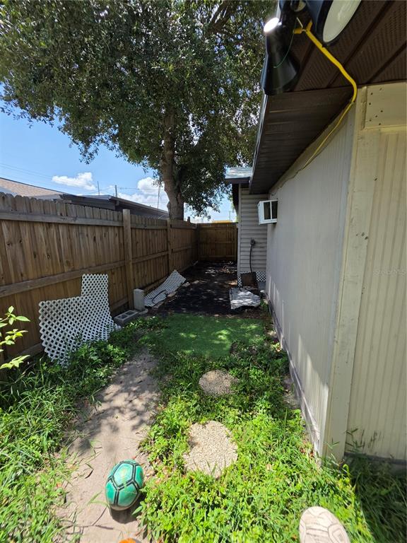 A narrow side yard features a wooden fence, patches of grass, and a wall-mounted air conditioner — 3308 E MOHAWK AVE, TAMPA, FL