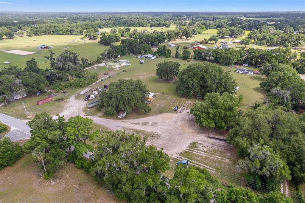 An aerial view shows a large, grassy rural property with scattered trees and several buildings — 1751 E HIGHWAY 329, CITRA, FL