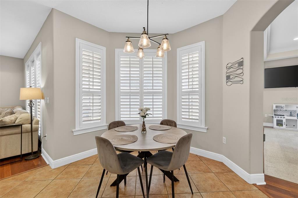 A dining area features a round wooden table, four gray chairs, and white plantation shutters — 1245 SHORECREST CIR, CLERMONT, FL