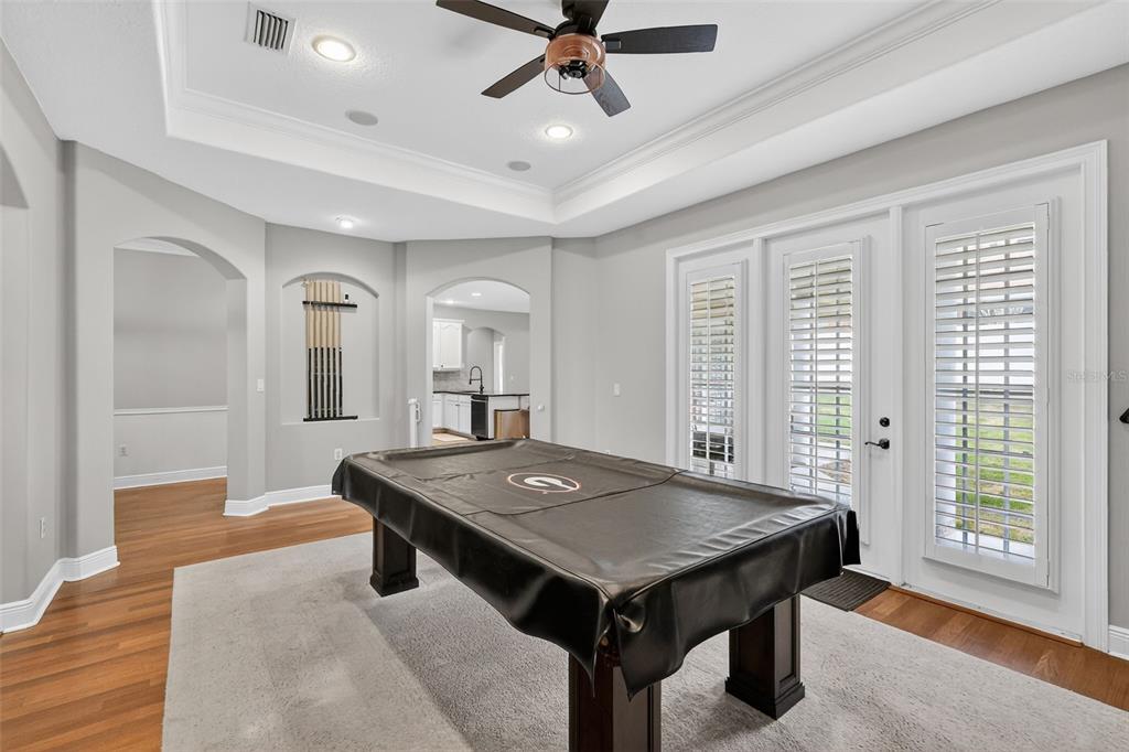 A game room features a pool table, a tray ceiling with a fan, and glass doors — 1245 SHORECREST CIR, CLERMONT, FL