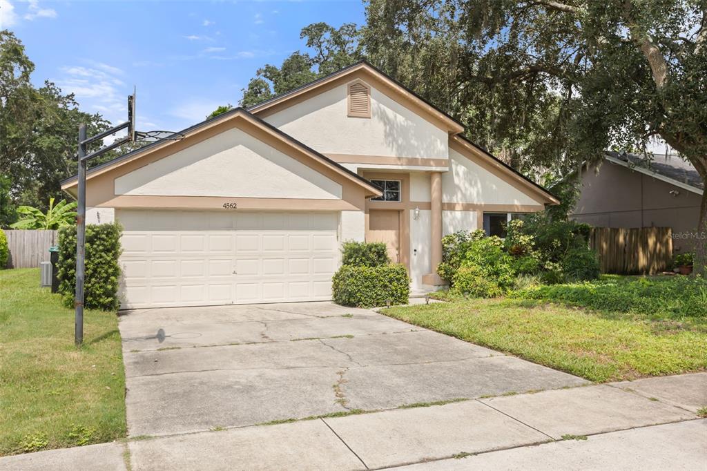 A single-story house with a beige stucco exterior, a two-car garage, and a concrete driveway — 4562 CONWAY LANDING DRIVE, ORLANDO, FL