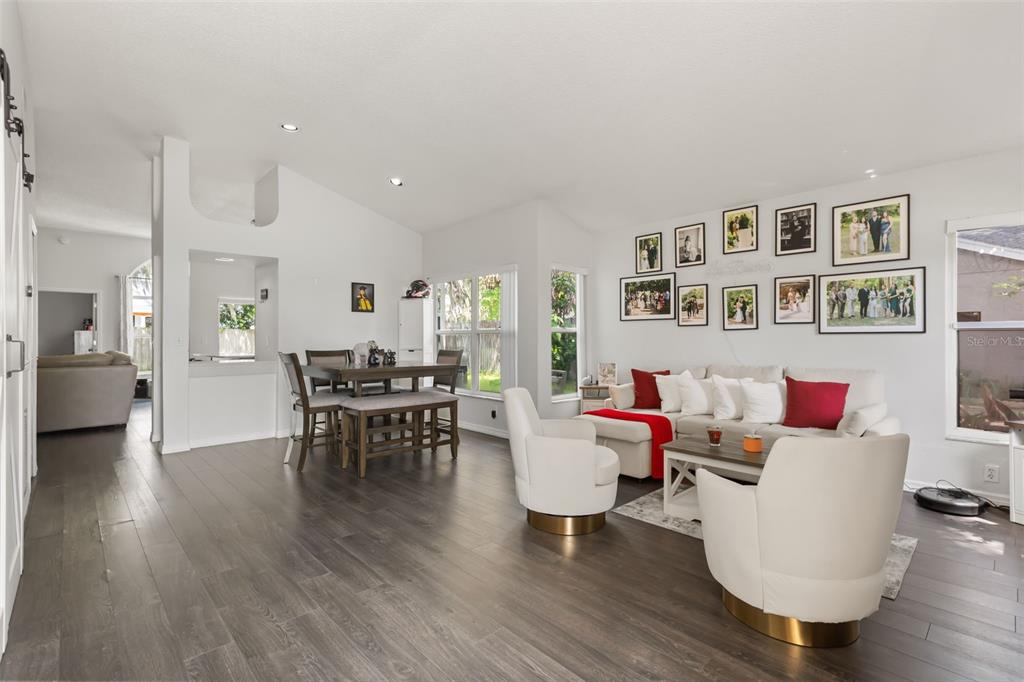 A bright living and dining area with white walls, dark wood flooring, and modern furniture — 4562 CONWAY LANDING DRIVE, ORLANDO, FL