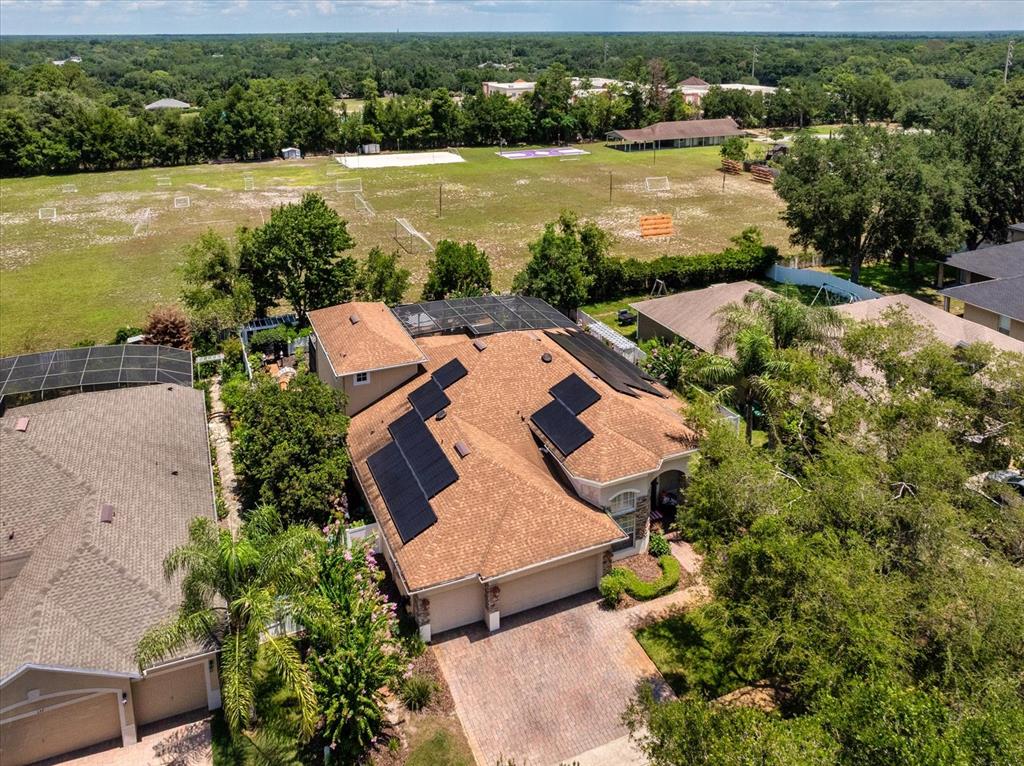 An aerial view shows a house with solar panels on its roof and a large yard — 131 ALEXANDRIA PLACE DRIVE, APOPKA, FL