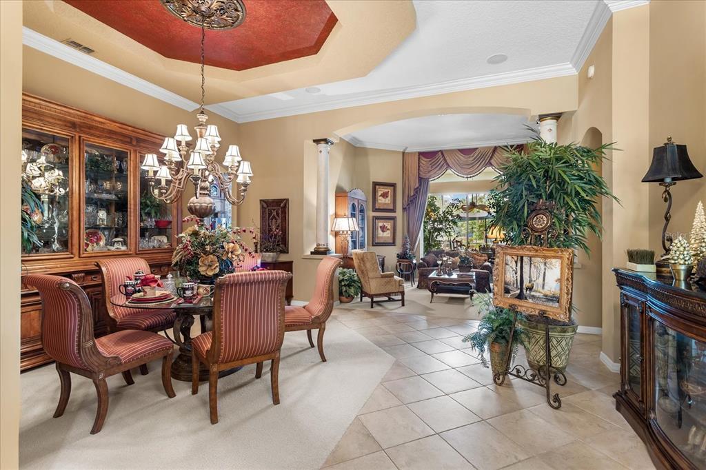 A formal dining room with a tray ceiling, chandelier, and adjacent living area — 131 ALEXANDRIA PLACE DRIVE, APOPKA, FL