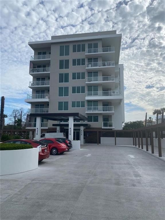 A multi-story modern apartment building with balconies stands above a paved parking lot — 920 N OSCEOLA AVENUE UNIT 405, CLEARWATER, FL