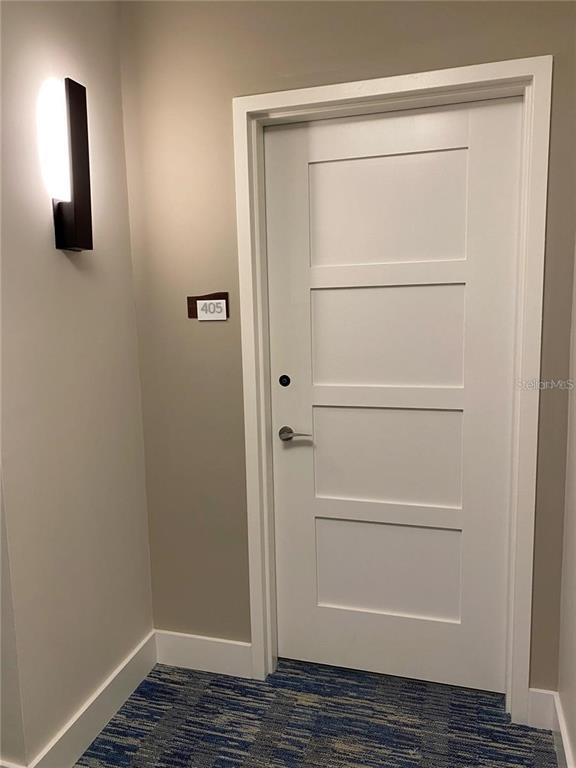 A white four-panel door with a room number sign is located in a carpeted hallway — 920 N OSCEOLA AVENUE UNIT 405, CLEARWATER, FL