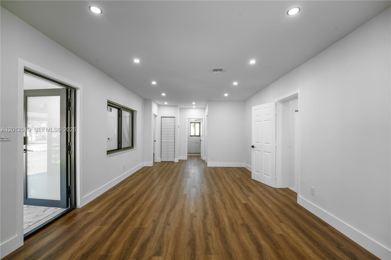 A modern kitchen features white cabinets, gold hardware, marble-patterned backsplashes, and a large quartz island — 220 NW 144th St, Miami FL 33168, MIAMI, FL