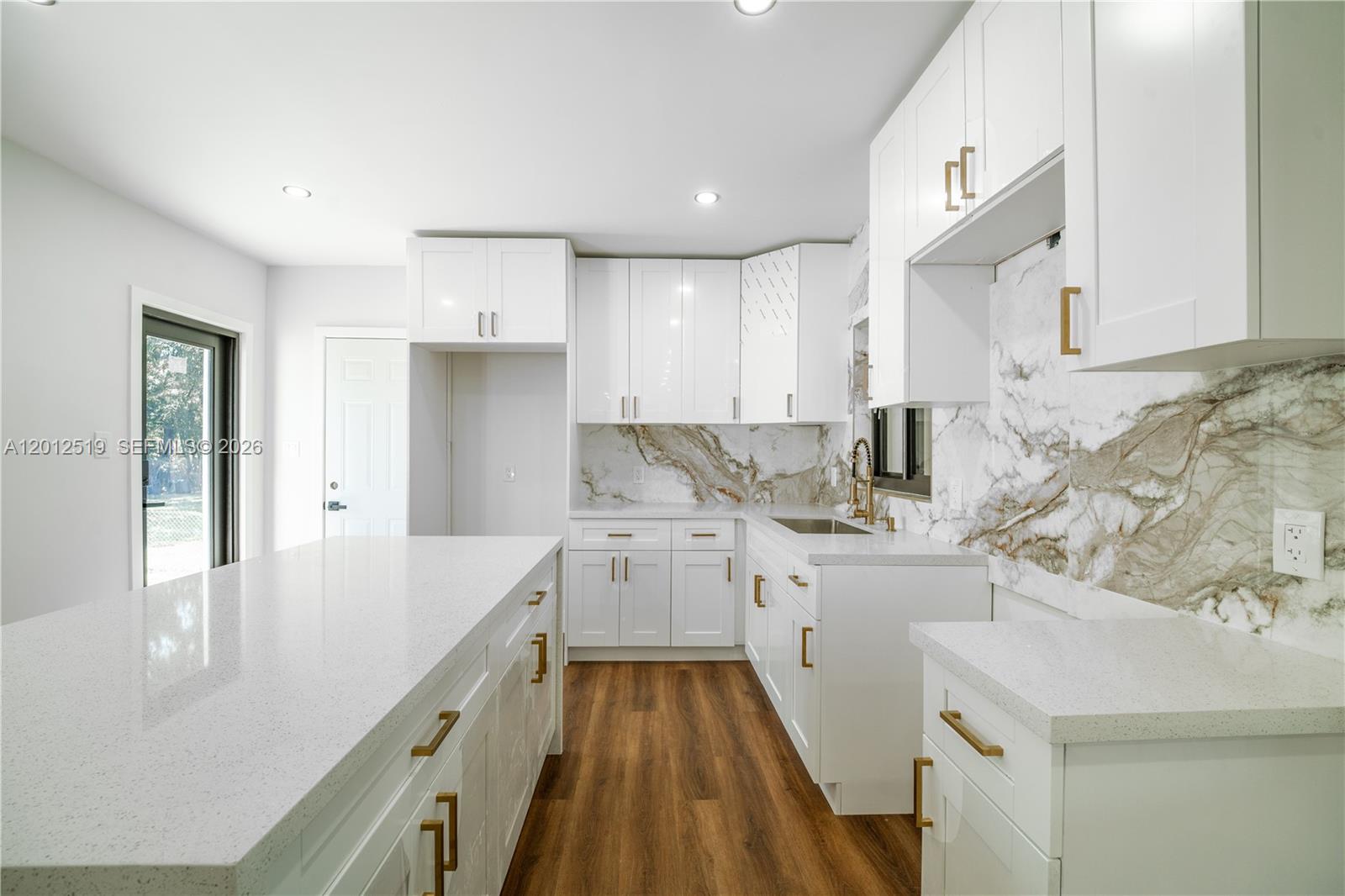 A bright, empty room features white walls, recessed lighting, and wood-look flooring — 220 NW 144th St, Miami FL 33168, MIAMI, FL