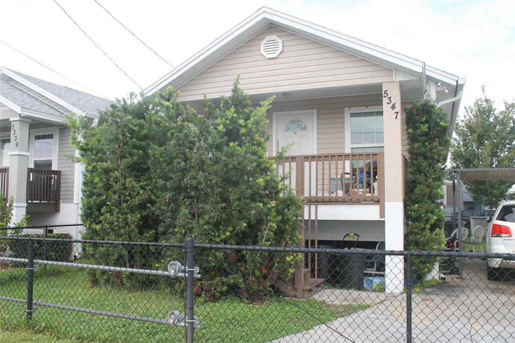 A tan house with a front porch and a chain-link fence in the yard — 5347 LEISURE LN, NEW PORT RICHEY, FL