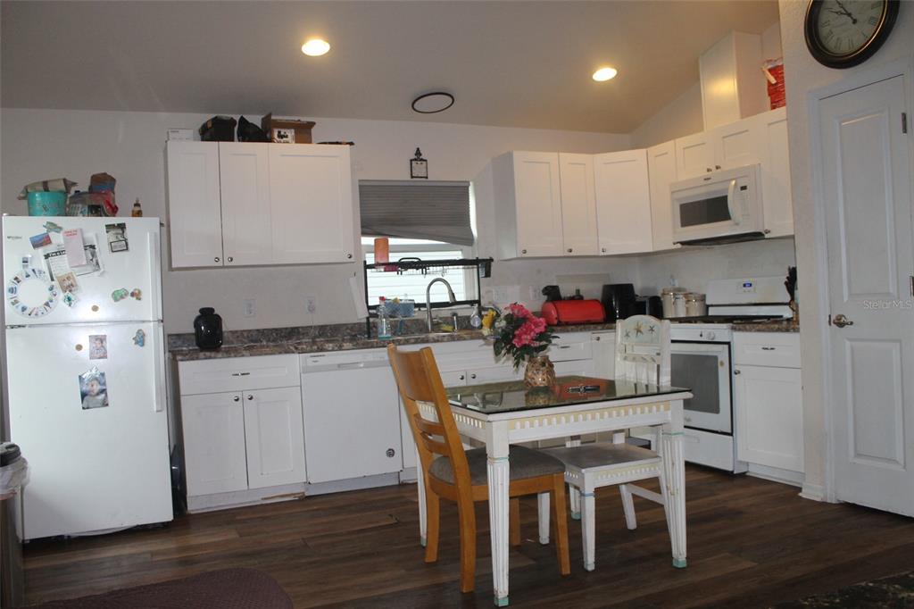 A kitchen features white cabinetry, a dining table, and a white refrigerator on wood flooring — 5347 LEISURE LN, NEW PORT RICHEY, FL