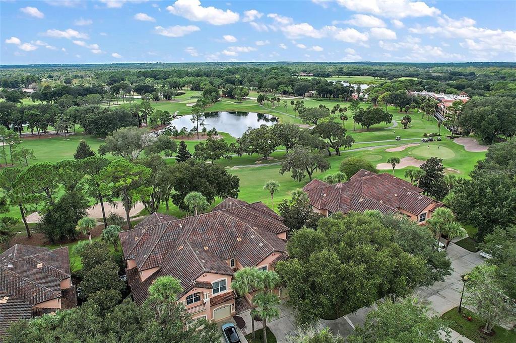 An aerial view of a multi-story house with a tile roof overlooking a golf course — 802 CAMINO REAL BOULEVARD UNIT 802, HOWEY IN THE HILLS, FL