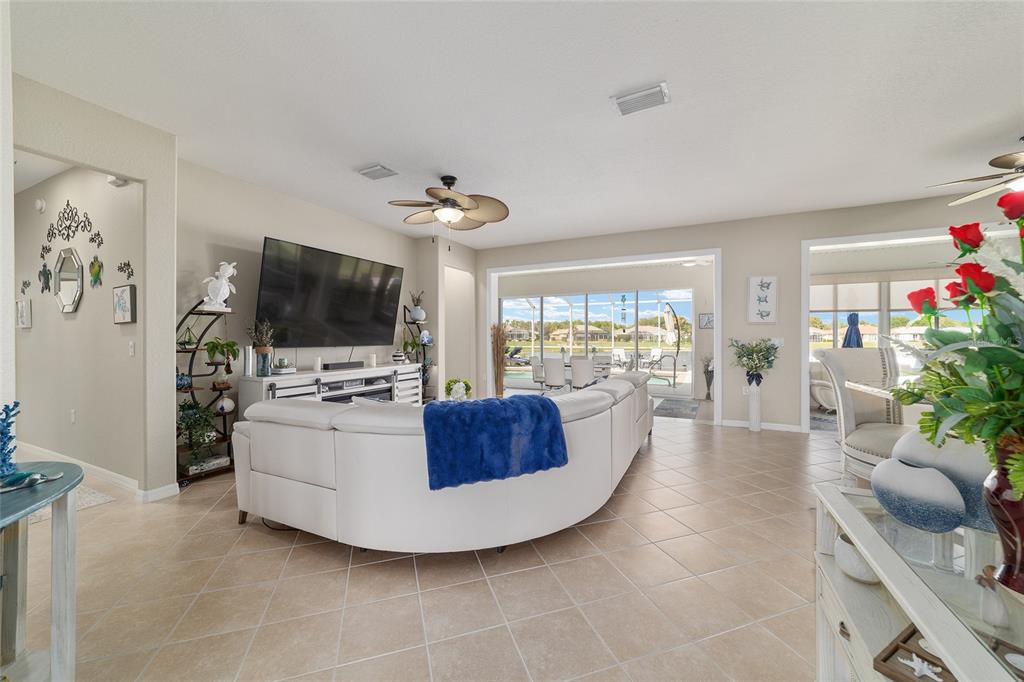 A living room features a white curved sectional sofa, a large television, and tile flooring — 9375 SE 125TH STREET, SUMMERFIELD, FL