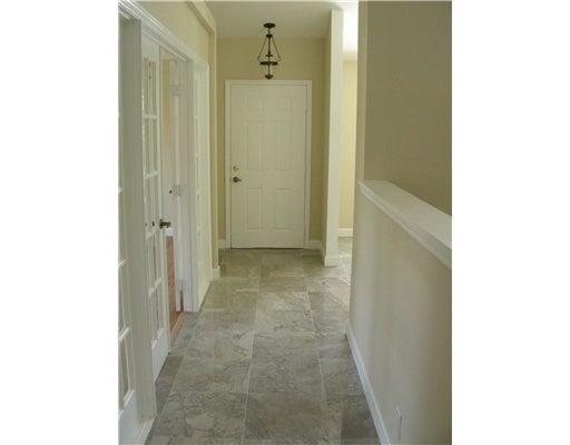 A hallway with light-colored tile flooring leads to a white front door under a chandelier — 19600 Sea Pines Way, Boca Raton FL 33498, BOCA RATON, FL
