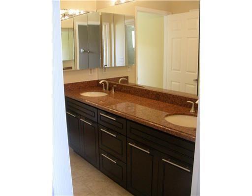 A bathroom vanity with a granite countertop, dual sinks, and dark wood cabinets — 19600 Sea Pines Way, Boca Raton FL 33498, BOCA RATON, FL