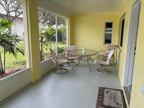 A screened-in porch with yellow walls, a glass-top table, and four chairs — 4404 SE Mulford Lane, Stuart FL 34997, STUART, FL