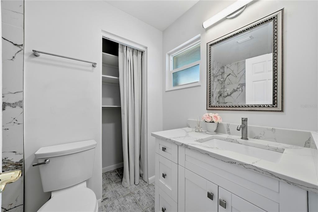 A bathroom features a white vanity with a marble countertop, a toilet, and a closet — 906 CARLTON ROAD, TARPON SPRINGS, FL