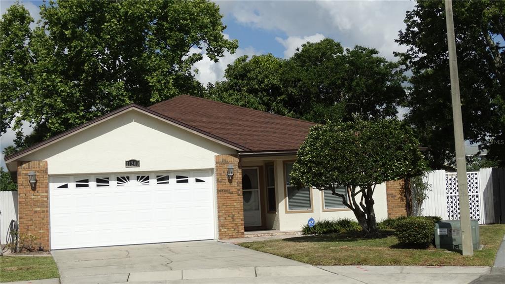 A single-story house with a white garage door, brick accents, and a brown shingled roof — 11200 TORBERT COURT, ORLANDO, FL