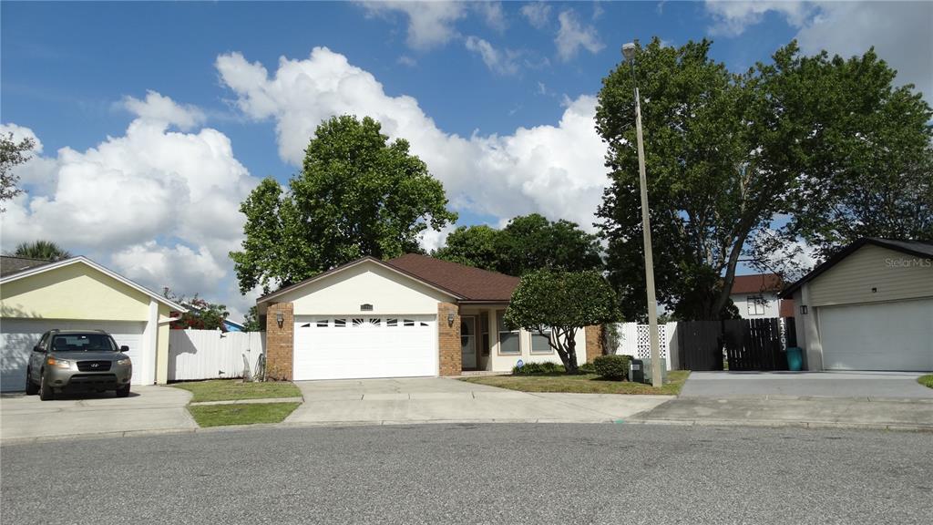 A single-story house with a white garage door and a driveway sits under a blue sky — 11200 TORBERT COURT, ORLANDO, FL