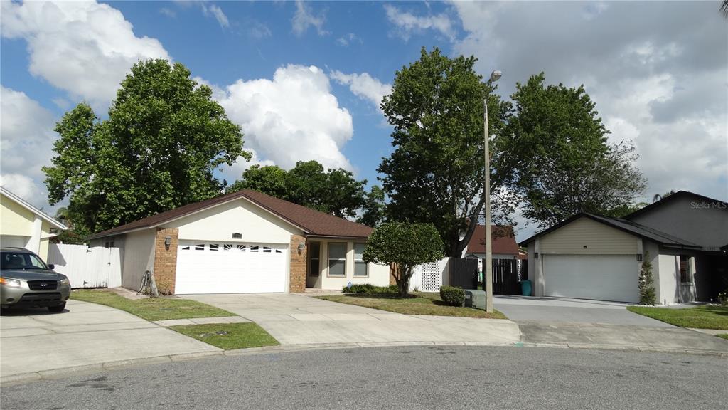 A street-level view of two single-story suburban houses with attached garages and driveways — 11200 TORBERT COURT, ORLANDO, FL