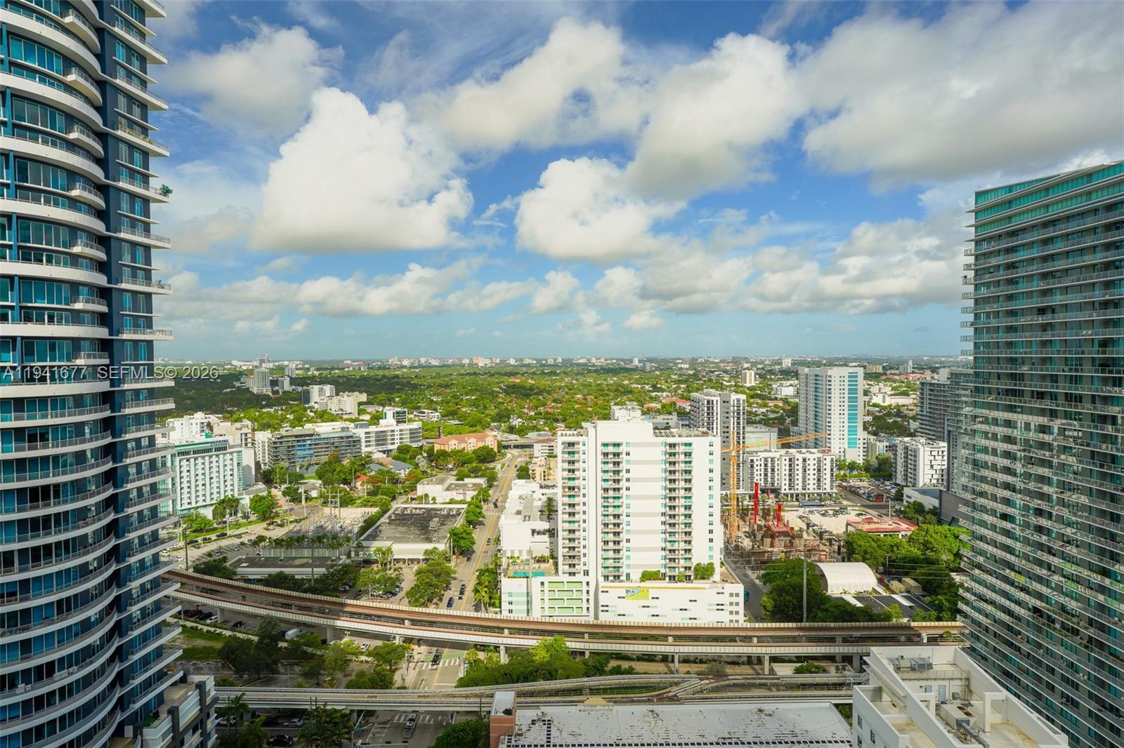 An elevated view shows a city skyline with tall residential towers and a transit track — 1250 S Miami Ave # 3003, Miami FL 33130, MIAMI, FL