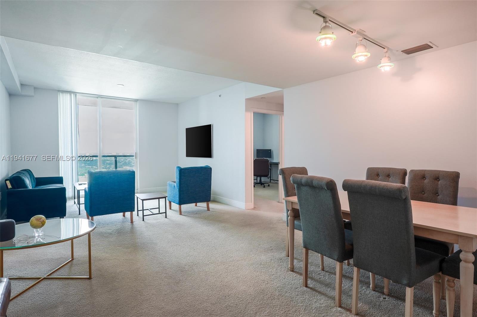 A living and dining area features blue armchairs, a dining set, and a balcony view — 1250 S Miami Ave # 3003, Miami FL 33130, MIAMI, FL