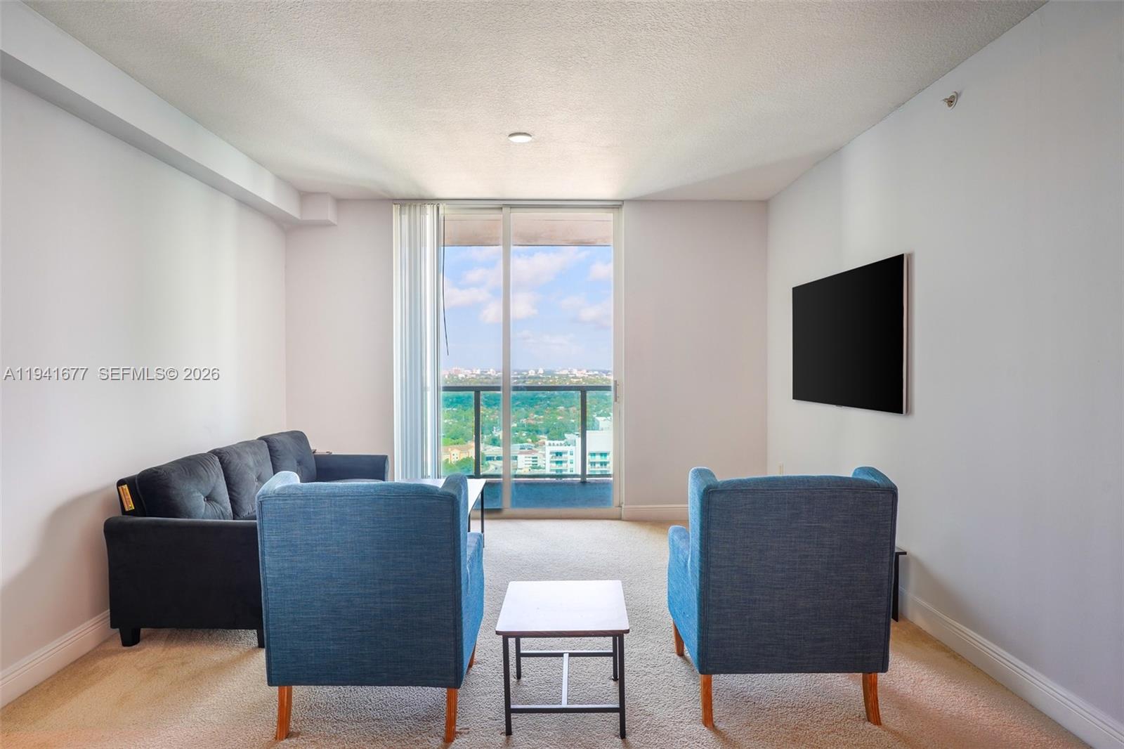 A living room features a dark sofa, two blue armchairs, and a balcony with views — 1250 S Miami Ave # 3003, Miami FL 33130, MIAMI, FL