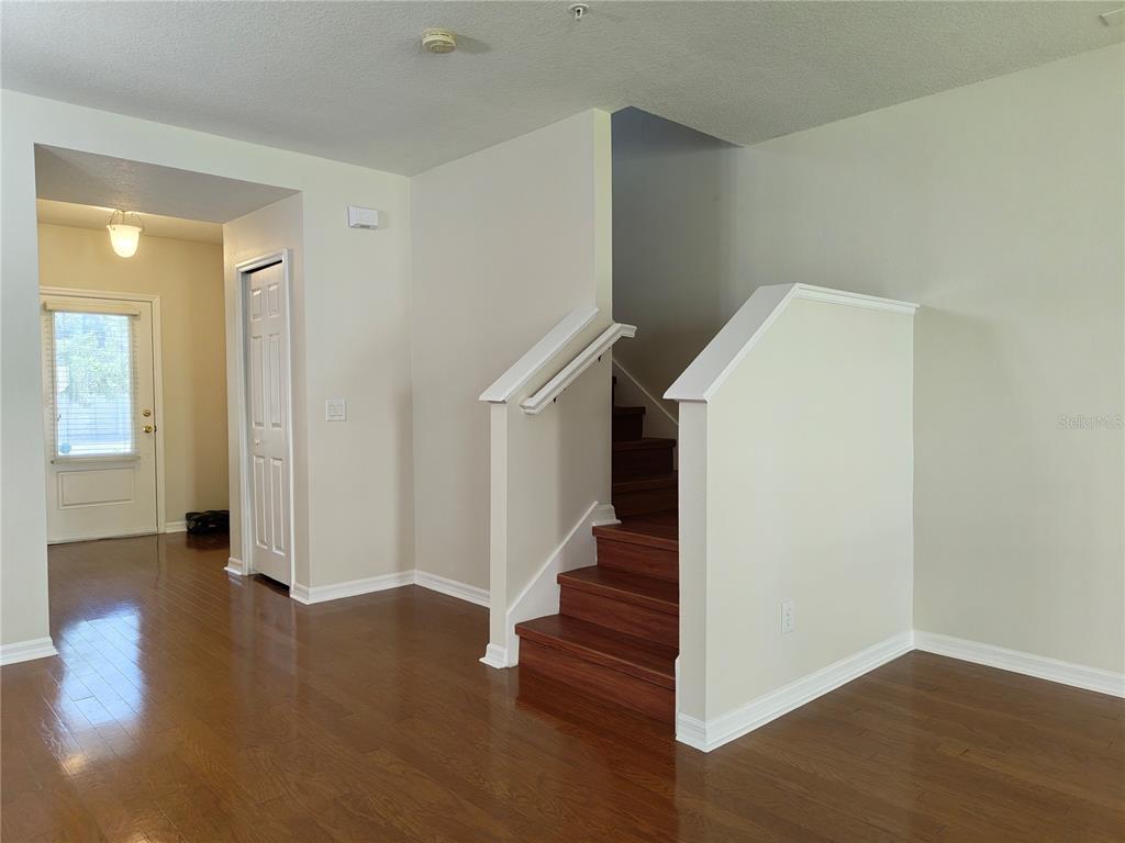 An interior view shows a staircase with wooden treads, white railings, and hardwood flooring — 2023 LACIE JO LANE, KISSIMMEE, FL