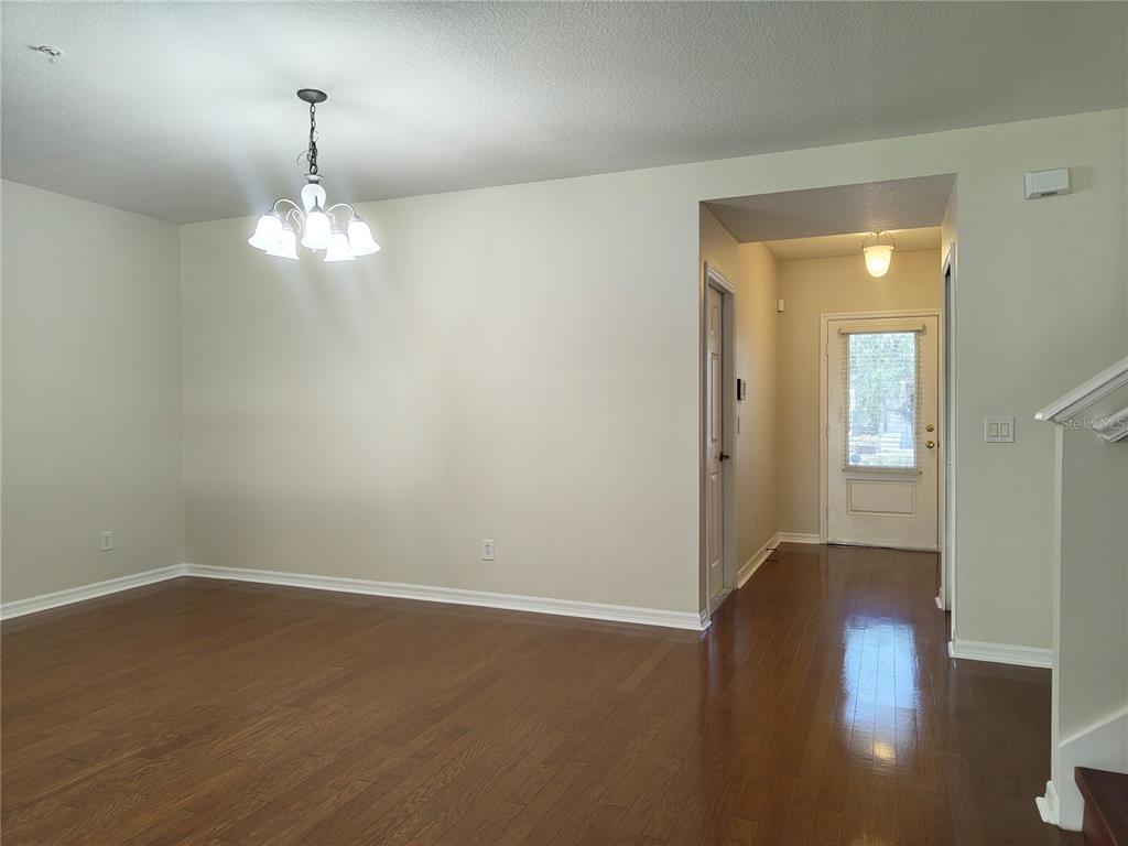 An empty dining area with hardwood floors, a chandelier, and a view of the entryway — 2023 LACIE JO LANE, KISSIMMEE, FL
