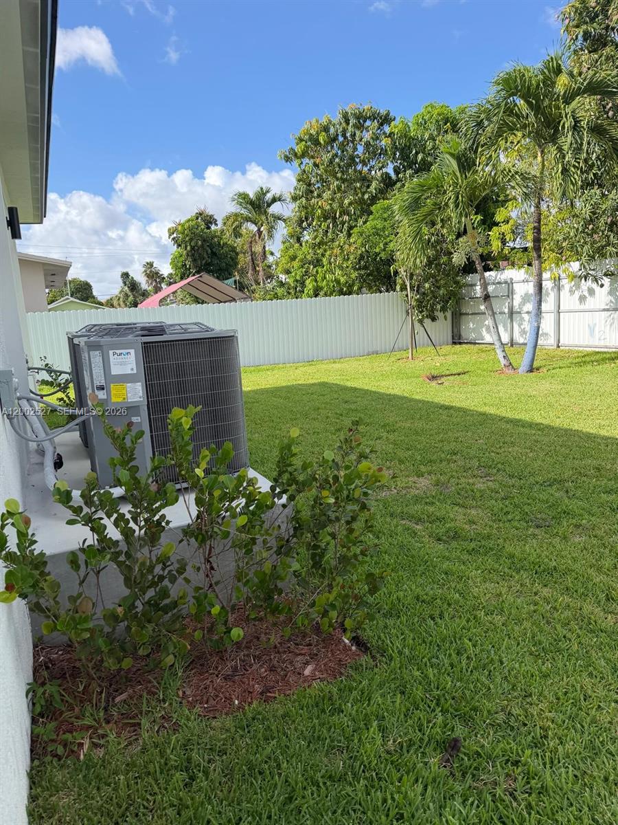 An outdoor air conditioning unit sits on a concrete pad in a grassy backyard — 831 SE 9th Ave, Hialeah FL 33010, HIALEAH, FL