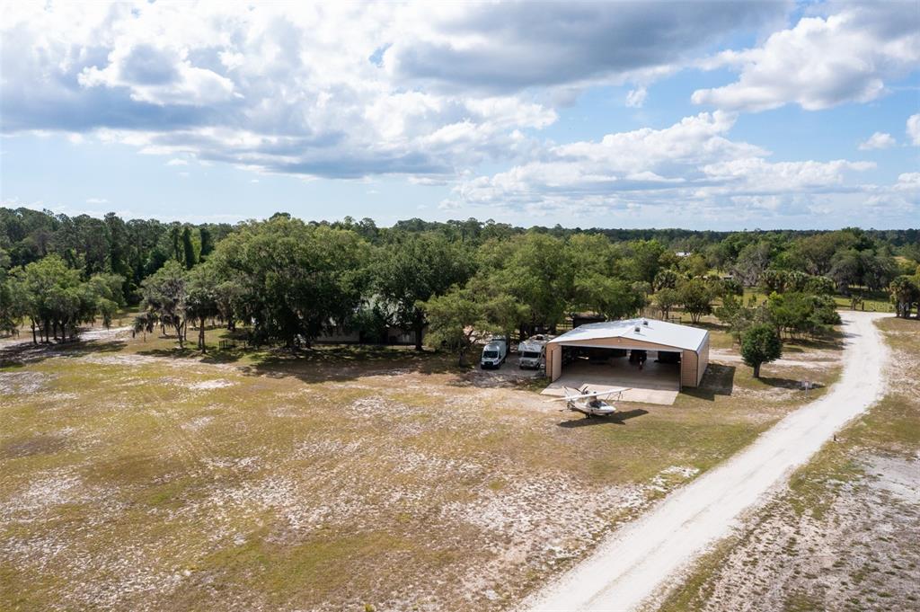An aerial view shows a large metal hangar with a small airplane parked outside — 1851 MAYTOWN ROAD, OAK HILL, FL
