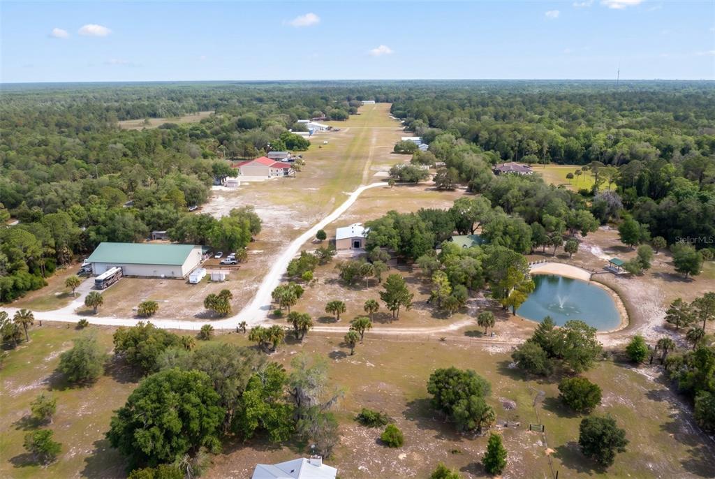 An aerial view shows a rural property with a private airstrip, outbuildings, and a pond — 1851 MAYTOWN ROAD, OAK HILL, FL
