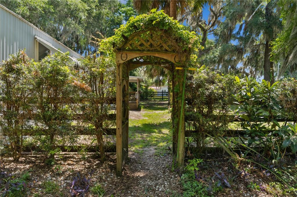 A wooden garden arbor stands over a path leading through a fence into a yard — 5891 SE 145TH STREET, SUMMERFIELD, FL