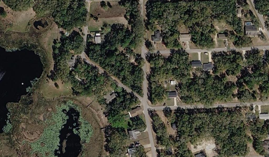 This aerial view shows a residential neighborhood with houses surrounded by trees and a lake — 0 SE 59TH PLACE, OCKLAWAHA, FL