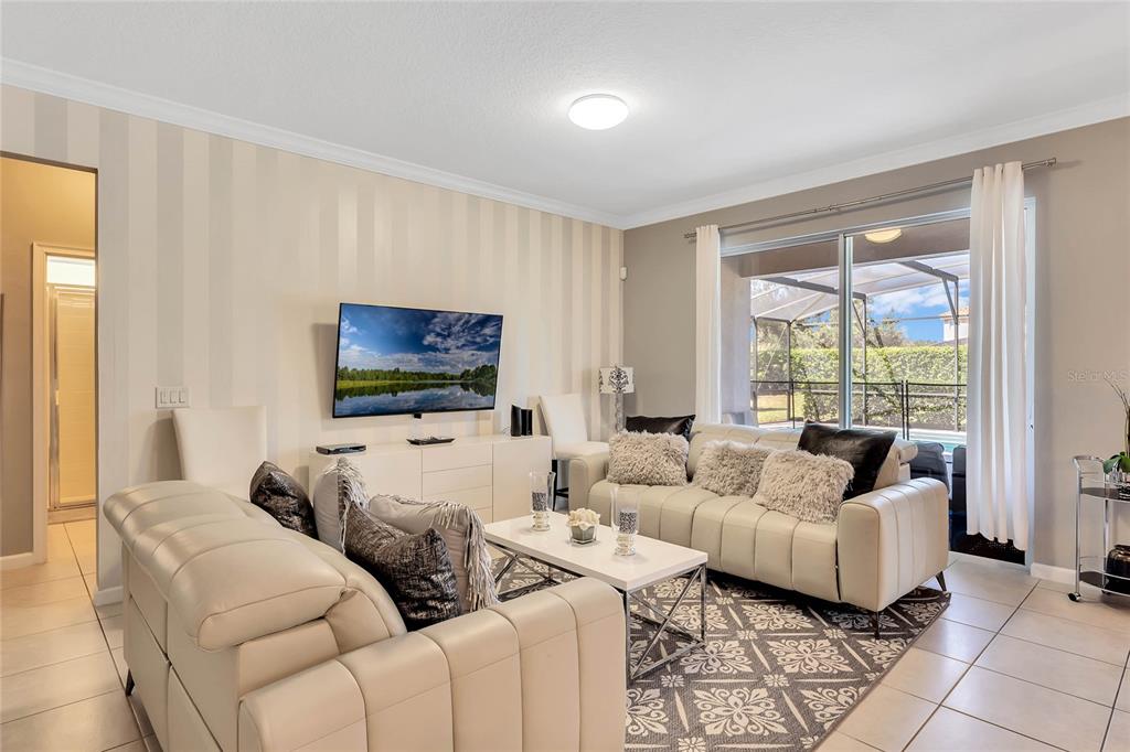 A living room features light-colored leather sofas, a patterned rug, and a sliding glass door — 4348 ACORN COURT, DAVENPORT, FL