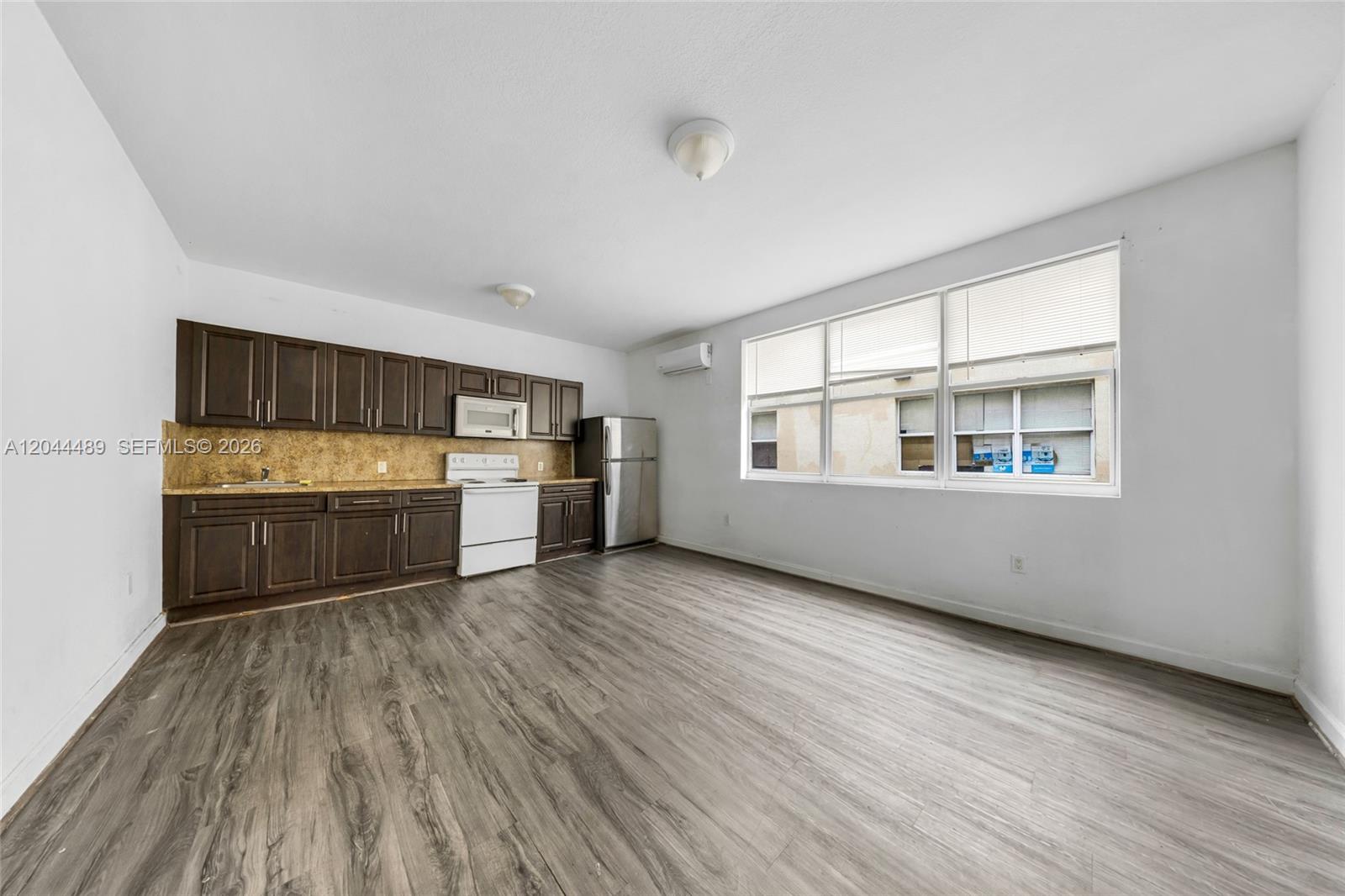 A kitchen with dark wood cabinets and stainless steel appliances opens into a living area — 1521 SW 7th St, Miami FL 33135, MIAMI, FL