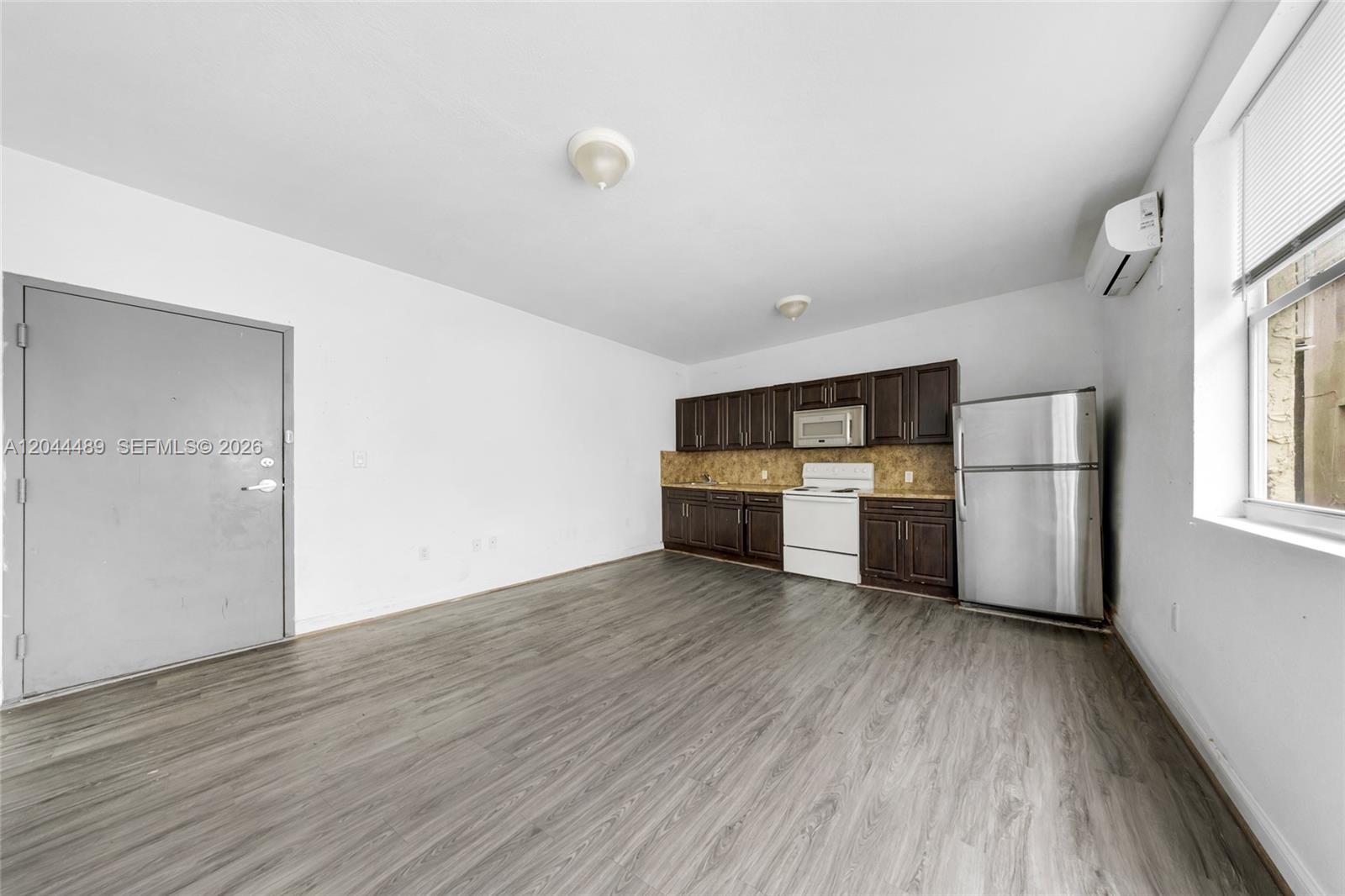 An open-concept kitchen and living area features dark wood cabinets and grey wood flooring — 1521 SW 7th St, Miami FL 33135, MIAMI, FL
