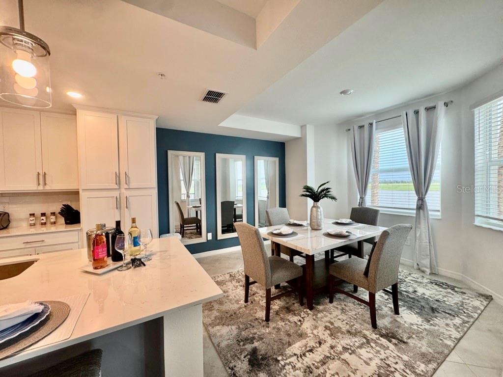 A dining area with a marble table, gray chairs, and a blue accent wall — 19116 SCALLOP LOOP UNIT 207, LAKEWOOD RANCH, FL