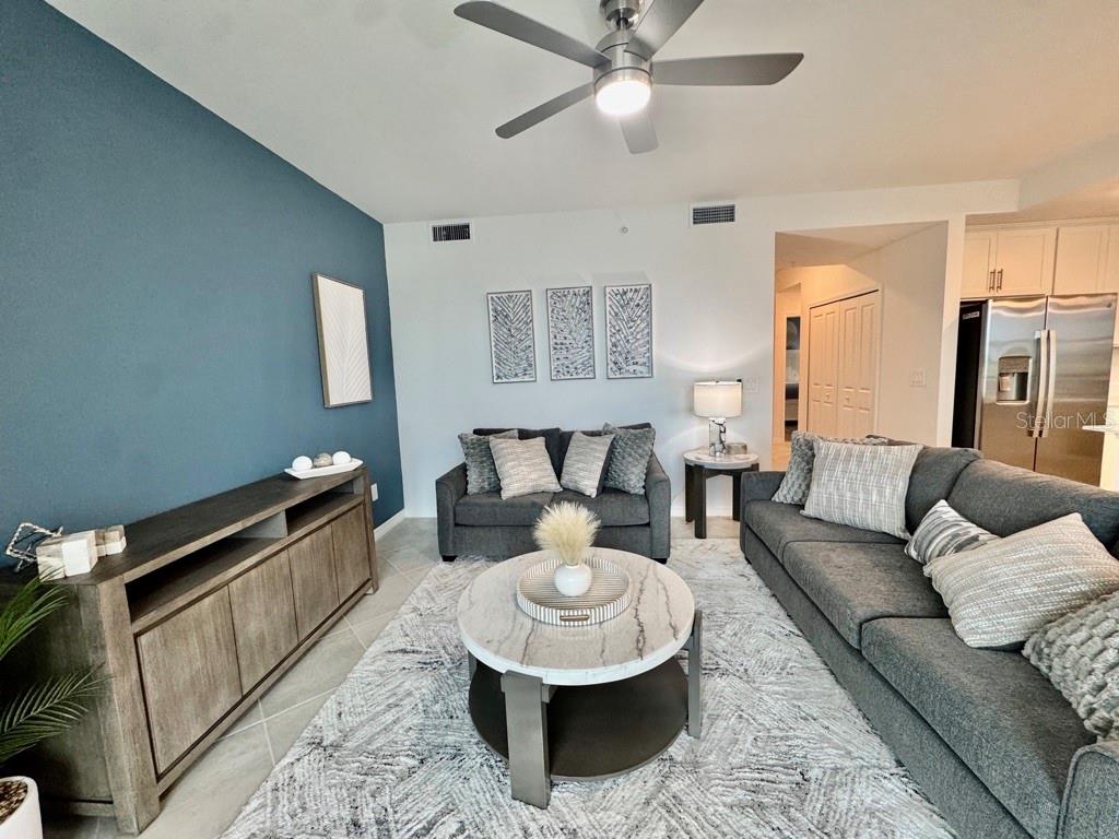 A living room features a blue accent wall, gray sofa, and a round marble coffee table — 19116 SCALLOP LOOP UNIT 207, LAKEWOOD RANCH, FL