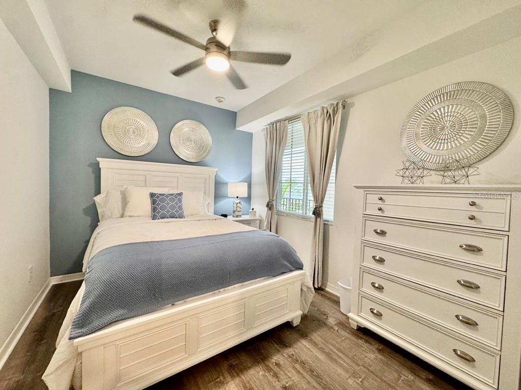 A bedroom features a white bed, a blue accent wall, and a white dresser — 19116 SCALLOP LOOP UNIT 207, LAKEWOOD RANCH, FL