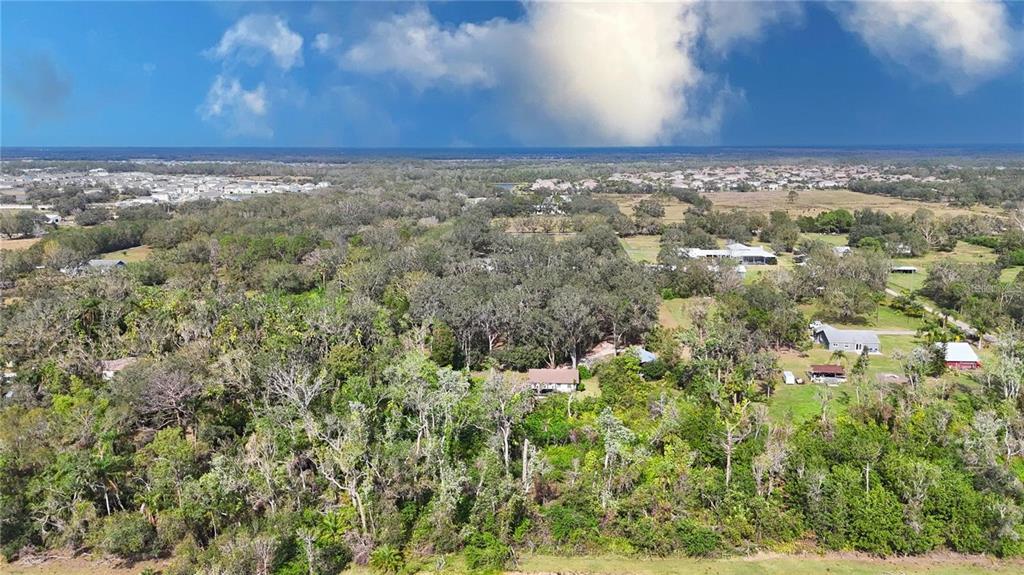 An aerial view shows a house nestled among dense trees in a rural landscape — 16678/16620 WATERLINE ROAD ROAD, BRADENTON, FL