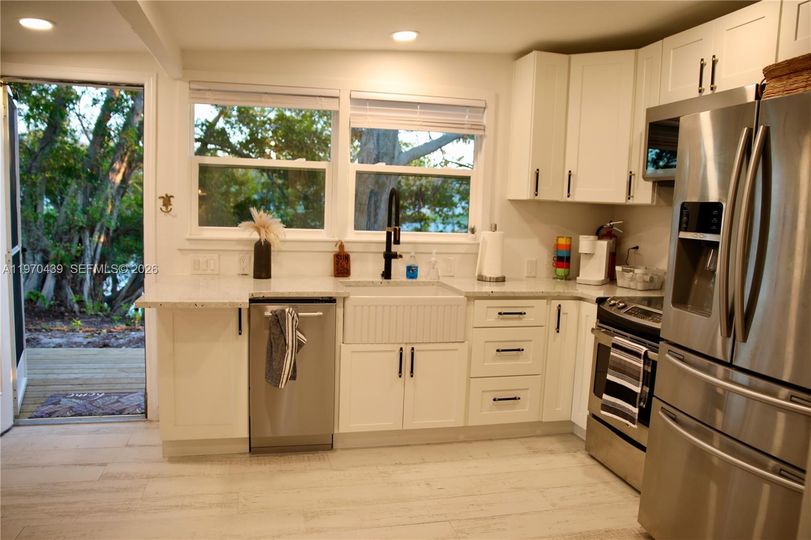A kitchen features white cabinets, stainless steel appliances, a farmhouse sink, and a back door — 124 Aucila RD., Cocoa Beach FL 32931, COCOA BEACH, FL