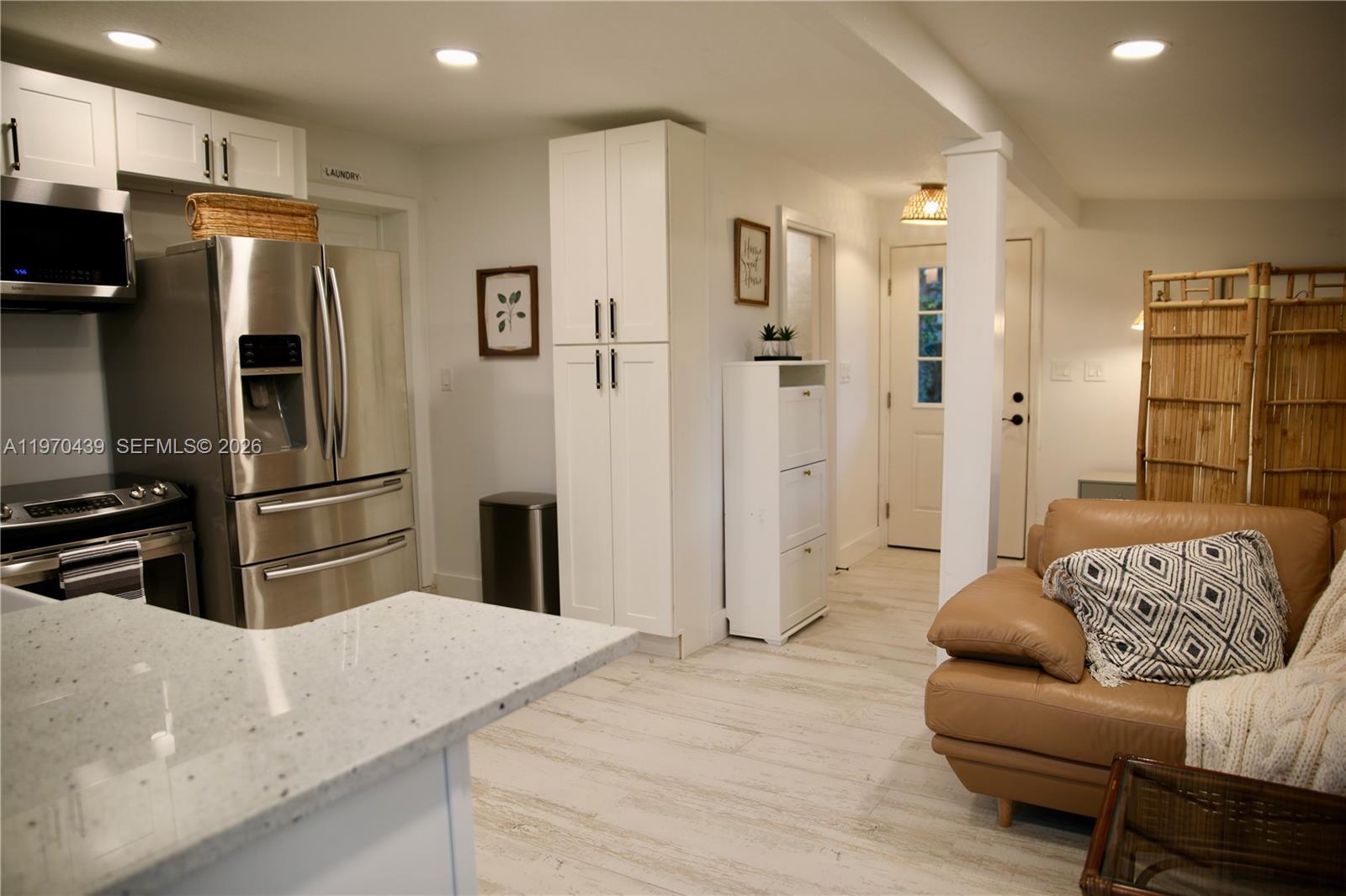 A kitchen with white cabinets and stainless steel appliances opens into a living area — 124 Aucila RD., Cocoa Beach FL 32931, COCOA BEACH, FL