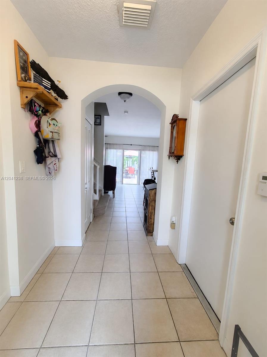 A tiled entryway leads through an arched doorway into a living area with patio access — 12850 SW 28th Ct, Miramar FL 33027, MIRAMAR, FL