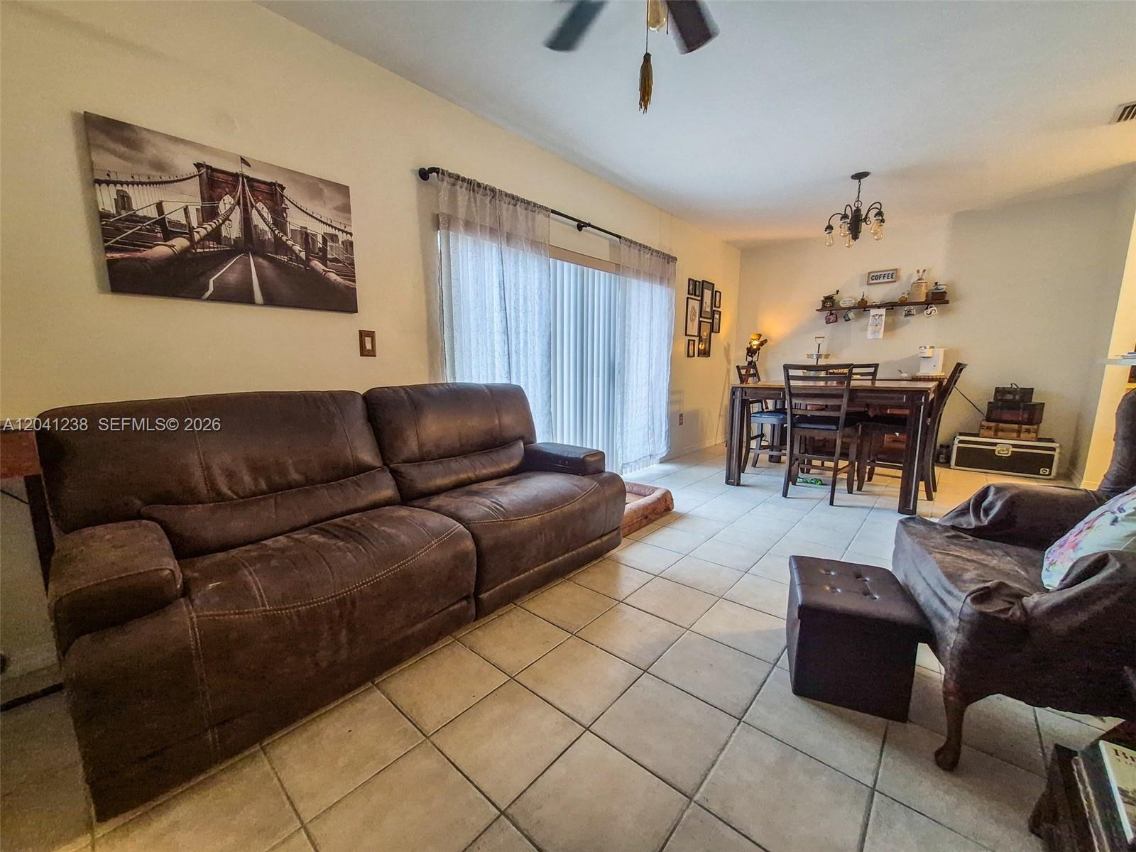 A living and dining area features tile flooring, a brown leather sofa, and a dining set — 12850 SW 28th Ct, Miramar FL 33027, MIRAMAR, FL