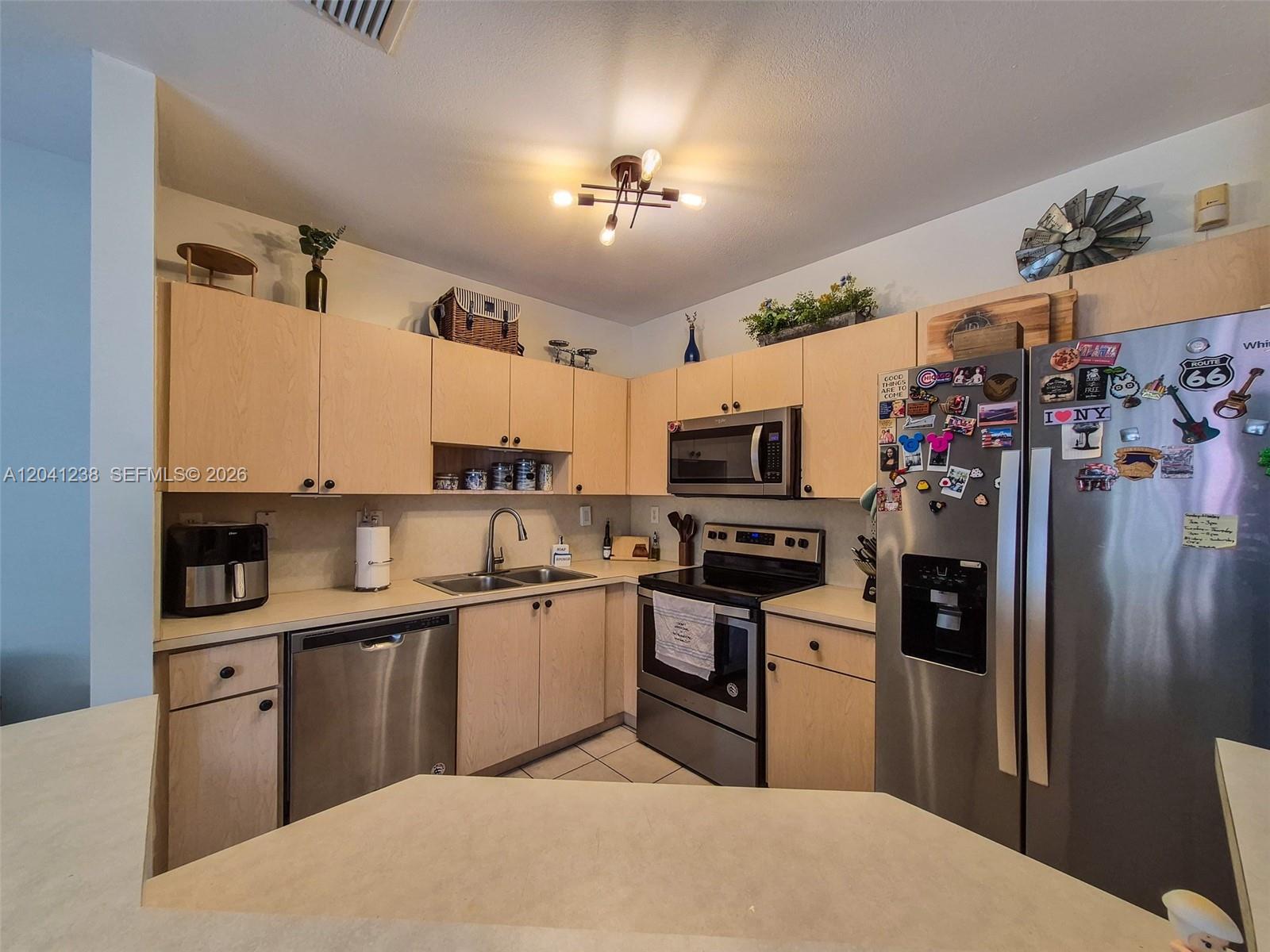 A kitchen features light wood cabinets, stainless steel appliances, and a tiled floor — 12850 SW 28th Ct, Miramar FL 33027, MIRAMAR, FL