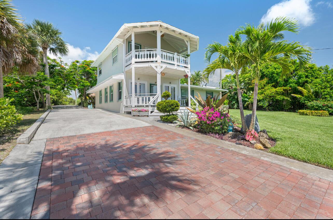 A two-story house with a balcony and a brick driveway surrounded by palm trees — 12417 S Indian River Drive, Jensen Beach FL 34957, JENSEN BEACH, FL