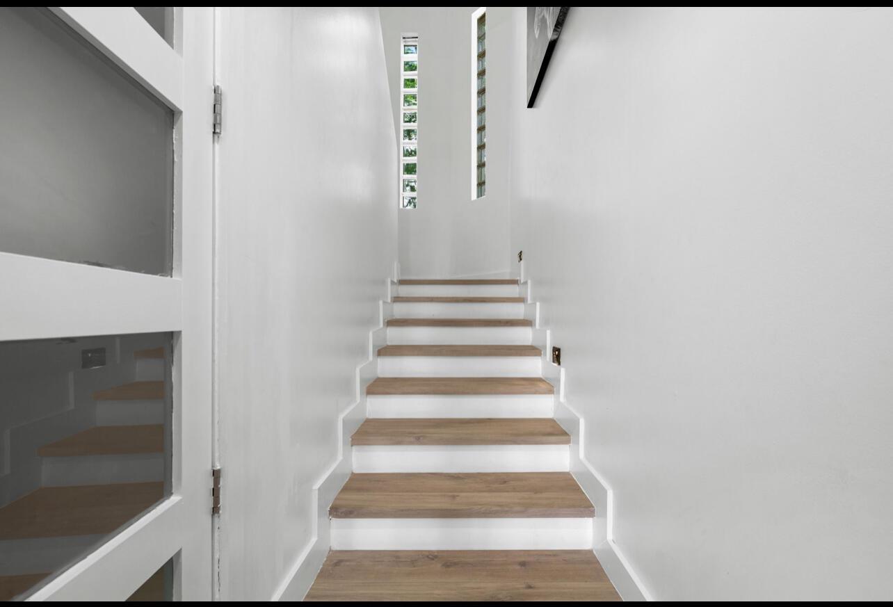 A straight staircase with wood treads and white risers leads up between two white walls — 12417 S Indian River Drive, Jensen Beach FL 34957, JENSEN BEACH, FL