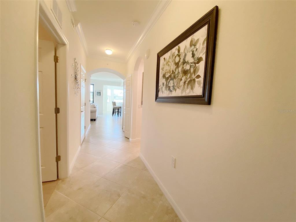 A tiled hallway leads through an arched doorway toward a bright living area — 16706 VARDON TERRACE UNIT 102, BRADENTON, FL