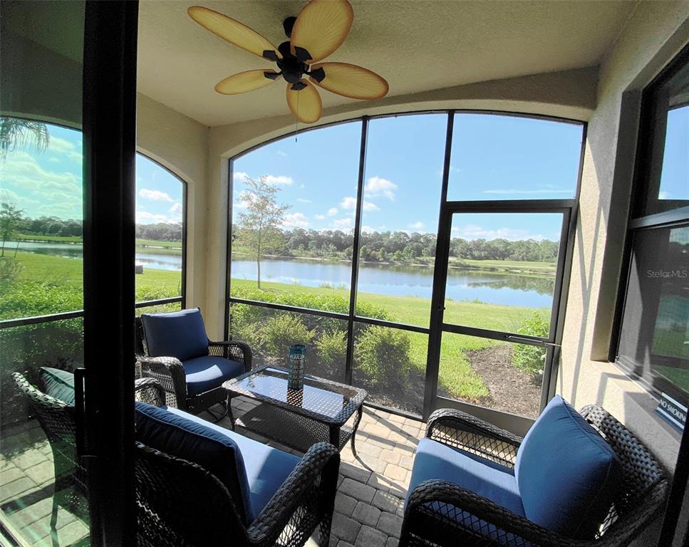 A screened-in patio features wicker furniture, a ceiling fan, and a view of a lake — 16706 VARDON TERRACE UNIT 102, BRADENTON, FL